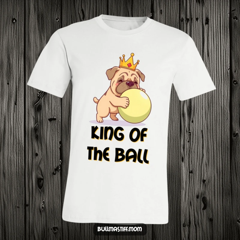 Funny Bullmastiff wearing a golden crown, gently pushing a large ball, expressing playful dominance on a t-shirt.